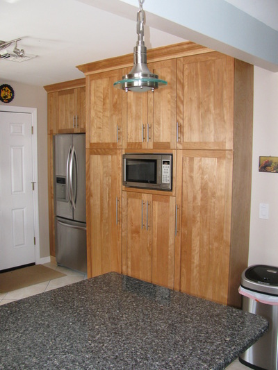 Remodeled cabinets in kitchen with fridge and microwave.