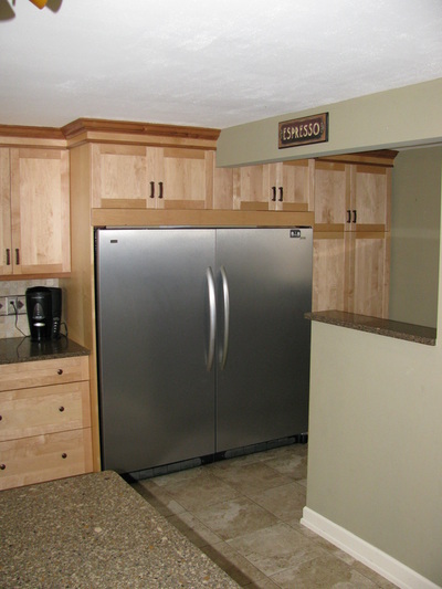 Remodeled cabinets in kitchen surrounding fridge.